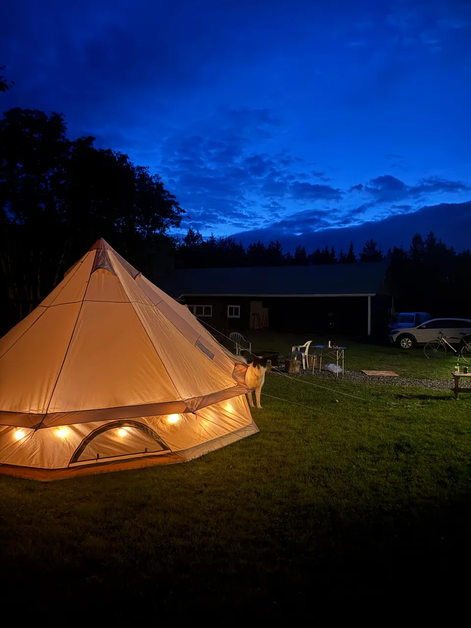 Une tente tipi éclairée de l’intérieur à la tombée de la nuit.